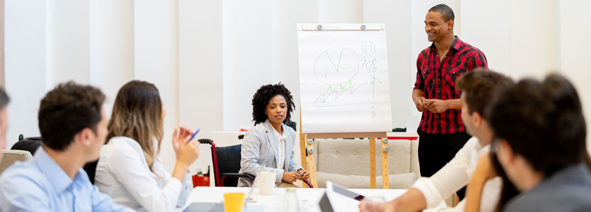 Woman in wheelchair leads business meeting as colleagues watch her presentation