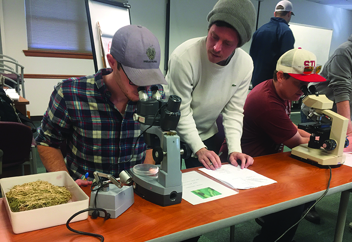 Turf students look through microscope to identify turf diseases