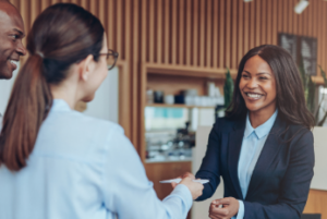 Two happy customers are helped by a smiling, attentive customer service professional