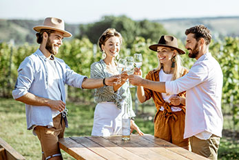 Group of Four Friends Toasting Each Other and Tasting Wine at a Vineyard
