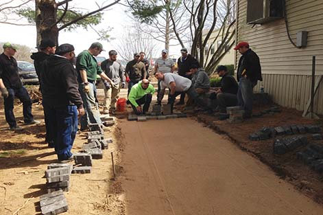 Instructor Alex Burke directs students as they lay pavers