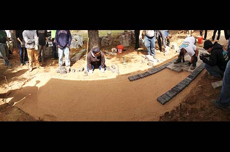 Landscaping student watches as a classmate lays pavers in a new walkway during a hands-on course at Rutgers.