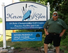 Golf Course Superintendent Jason Pierce next to Heron Glen golf course sign