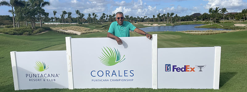 Julio Diaz standing behind Corales Puntacana Championship sign