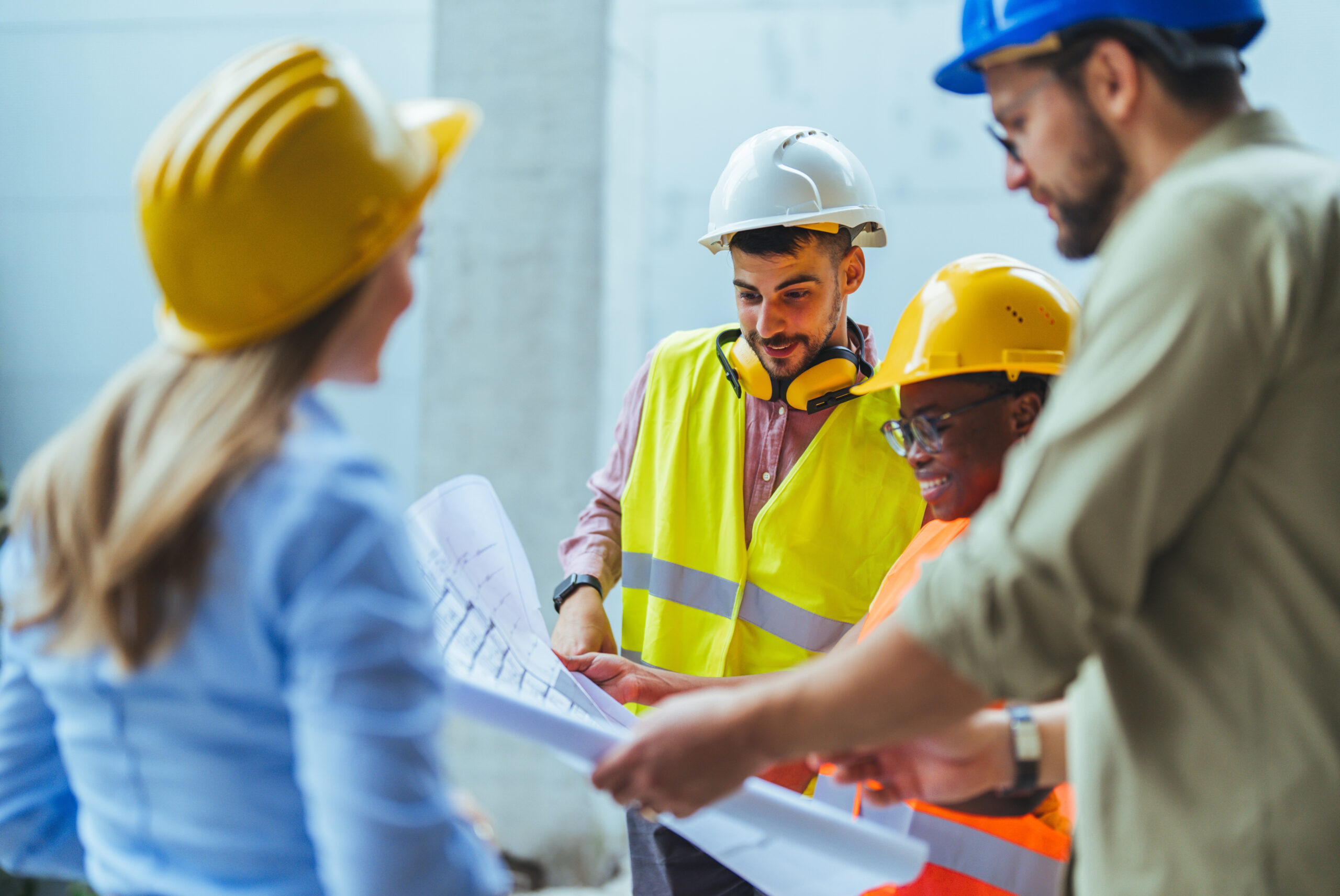 Team of diverse men and women construction workers discussing site plans