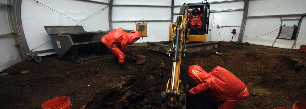 Environmental professionals in protective gear carrying out remediation of a contaminated site