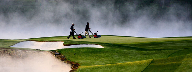 Steam rises behind turf managers working on the greens at Quail Hollow Club