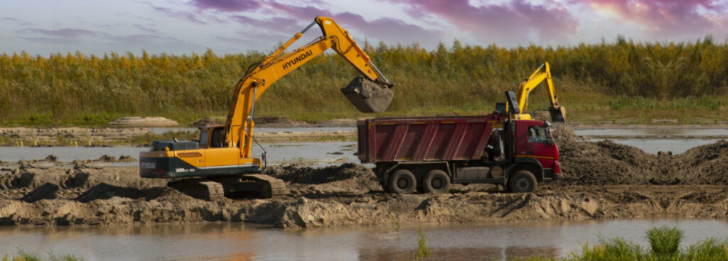 Excavator and dump truck at a wetland construction site