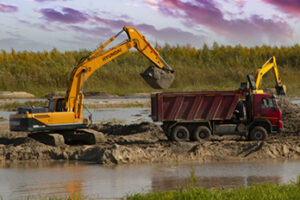 Excavator and dump truck at a wetland construction site