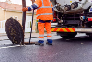 worker cleaning and maintaining the sewers on the roads