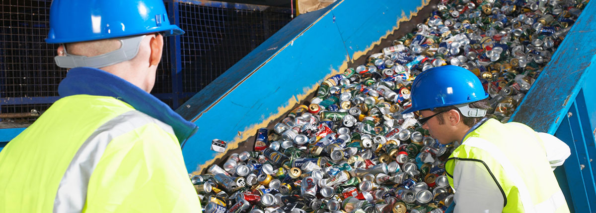 Two recycling center workers monitoring conveyor belt of recycled cans