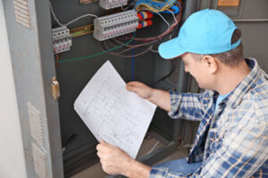 Electrician with Circuit Diagram near Distribution Board