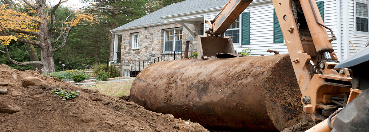 Construction vehicle removing heating oil storage tank from yard