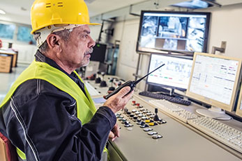 Senior Technician wearing hard hat and holding handheld radio