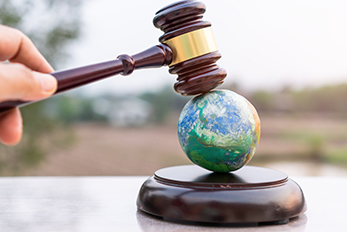 Judge's gavel coming down on small model of planet Earth representing environmental law
