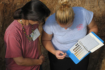 Two students compare soil samples to the Munsell Color Chart.