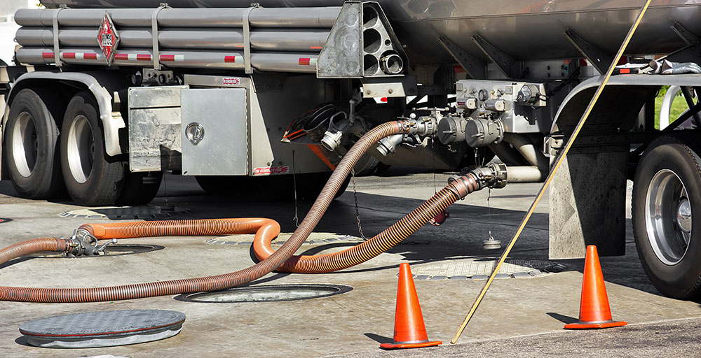 Fuel tanker deposits gasoline into storage tank at the gas station.