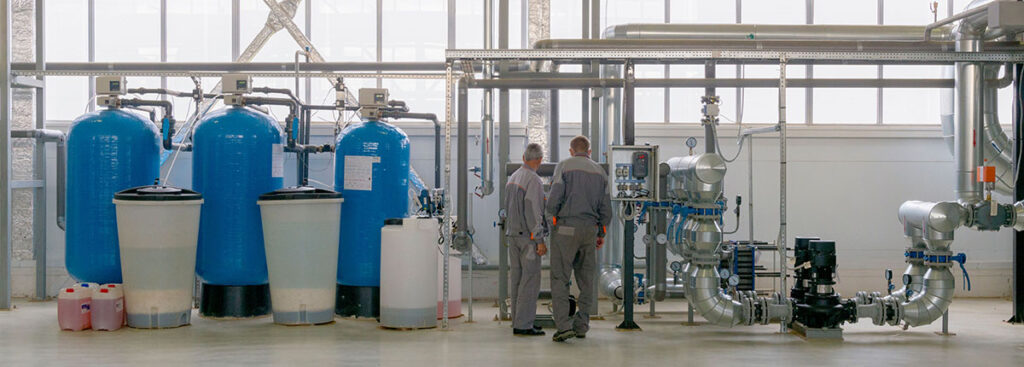 Two workers examining equipment at industrial water treatment plant