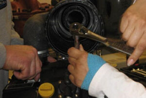 Two sets of hands working on repairing small engine