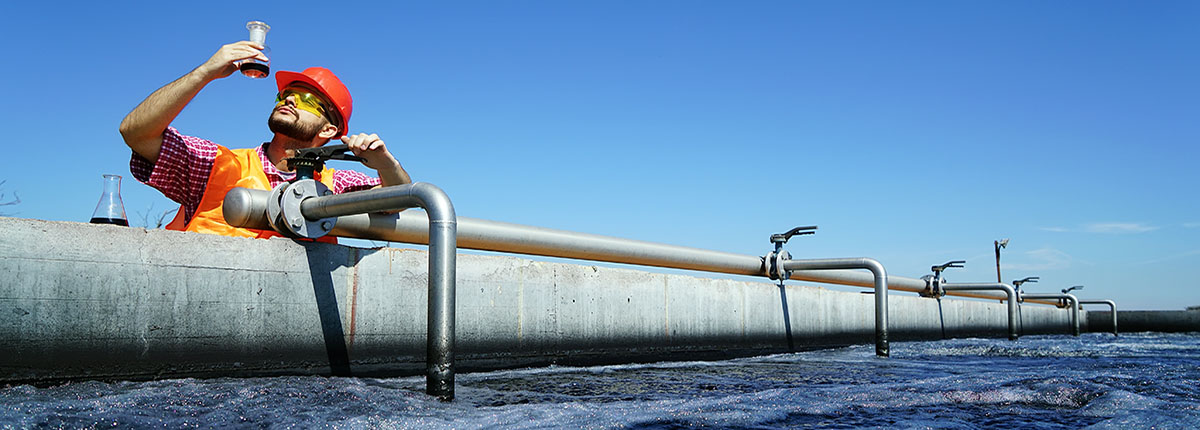 Wastewater operator checks sample by aerated activated sludge tank at a wastewater treatment plant