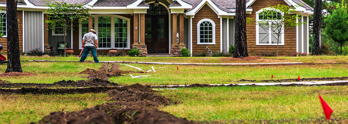 Freshly dug trenches for laying pipe to install a new irrigation system in a yard