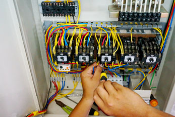 Electrical contactor doing wiring work in motor control panel