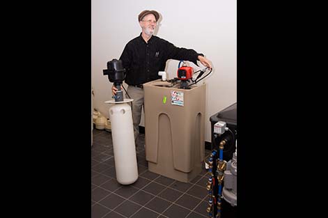 Instructor Bill Brodhead stands next to a radon mitigation system