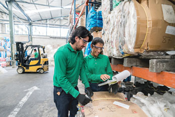 man and woman wearing plastic safety glasses working in a recycling center