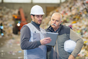 Workers at a recycling center looking at a tablet