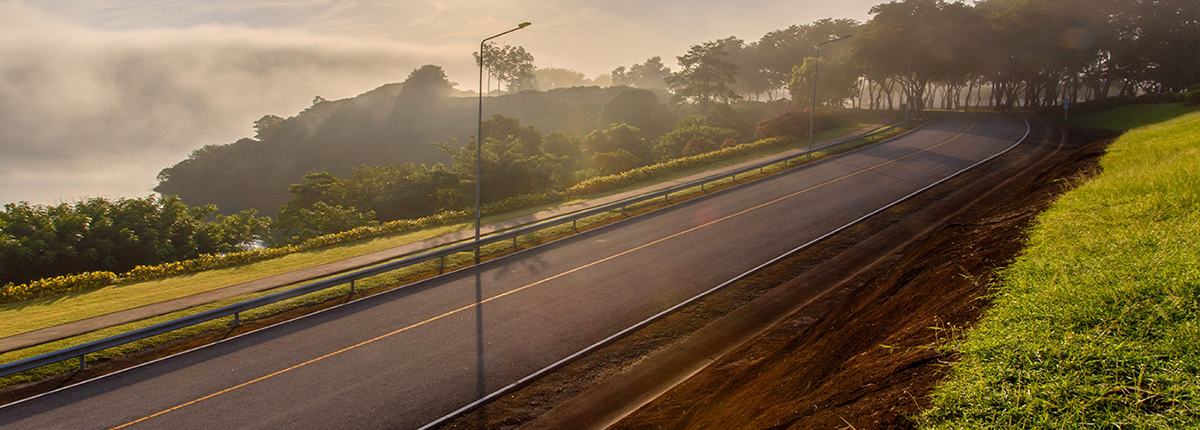 Turn in the road with guardrail and vegetation on either side