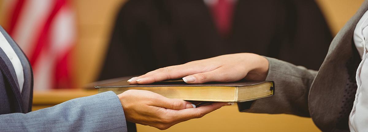 Witness swearing on the bible to tell the truth in court