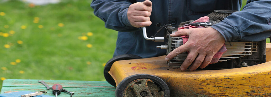 Man repairing lawn mower engine outside