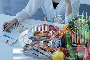 Charts and graphs overlayed on image of food scientist looking at data on clipboard next to food items on table