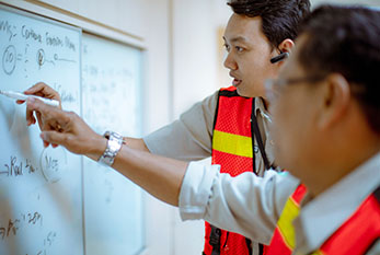 Two men writing on whiteboard and discussing how to solve a problem