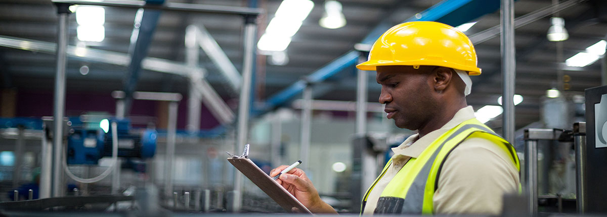 Man in hard hat writing on clipboard